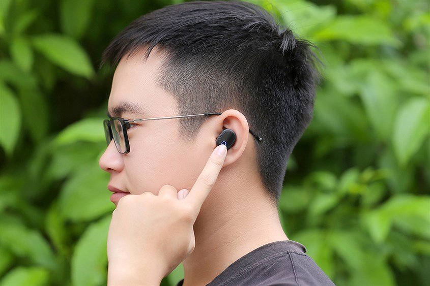 alt text: Người dùng nghe nhạc bằng tai nghe Bluetooth với âm lượng phù hợp