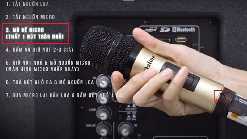 Mở nắp đế micro không dây để tiếp cận nút cài đặt bên trong, một bước trong quy trình khắc phục sự cố kết nối micro với loa bluetooth.