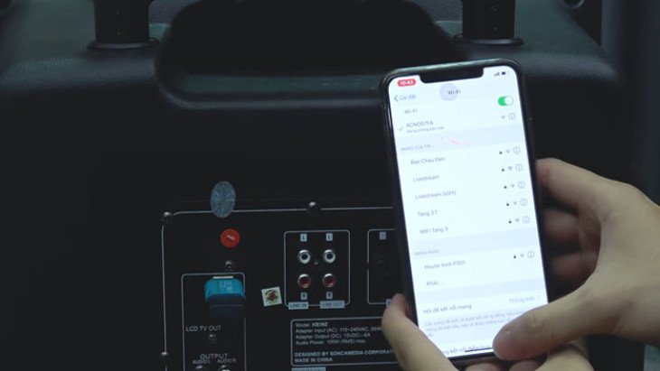 Một người phụ nữ đang kết nối bluetooth với loa kéo qua điện thoại để hát karaoke, biểu tượng cho sự tiện lợi.