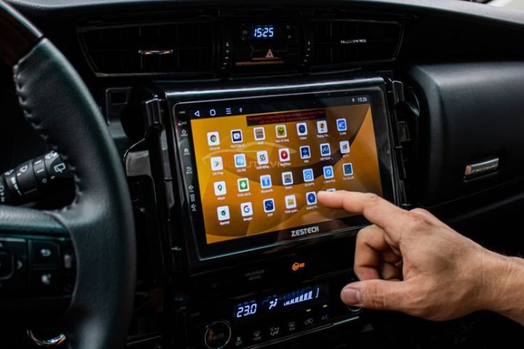 Người phụ nữ đang thao tác kết nối điện thoại với màn hình ô tô thông qua Bluetooth