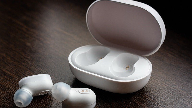 Bàn tay người dùng đang nhấn giữ nút nguồn trên tai nghe Bluetooth để khởi động lại