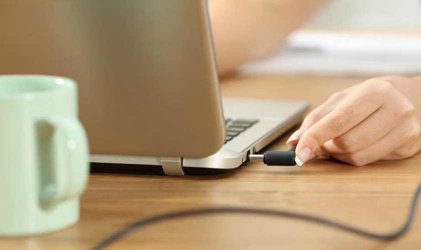 Cắm adapter sạc laptop vào ổ điện và laptop, minh họa trình tự sạc đúng cách để bảo vệ pin laptop Dell khỏi hư hại do sốc điện và trả lời câu hỏi sạc laptop Dell qua đêm có sao không một cách an toàn.