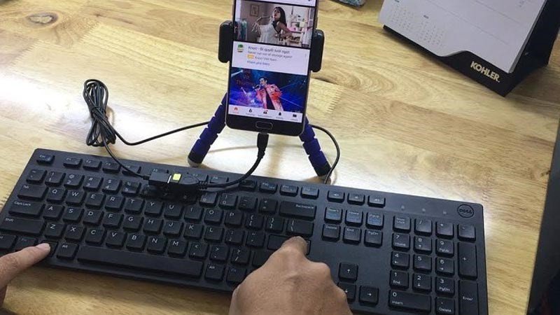 Cáp USB OTG đang kết nối bàn phím có dây với điện thoại thông minh, thể hiện cách kết nối bàn phím laptop với điện thoại bằng cáp
