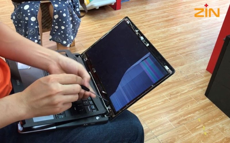 Hình ảnh cận cảnh kỹ thuật viên đang tháo cáp màn hình laptop Dell một cách cẩn thận