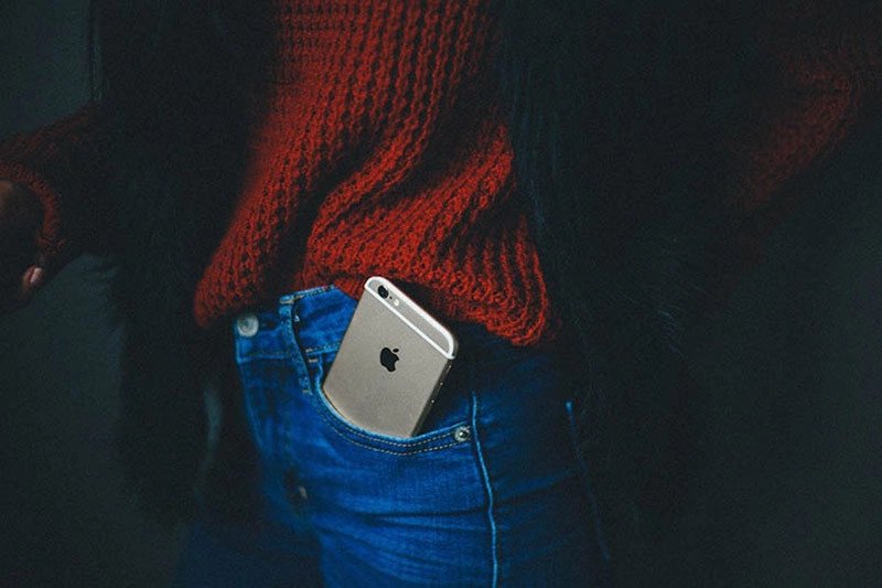 Hình ảnh điện thoại iPhone trong túi quần, minh họa nguyên nhân có thể gây kích hoạt khẩu lệnh tự động khi đeo tai nghe.