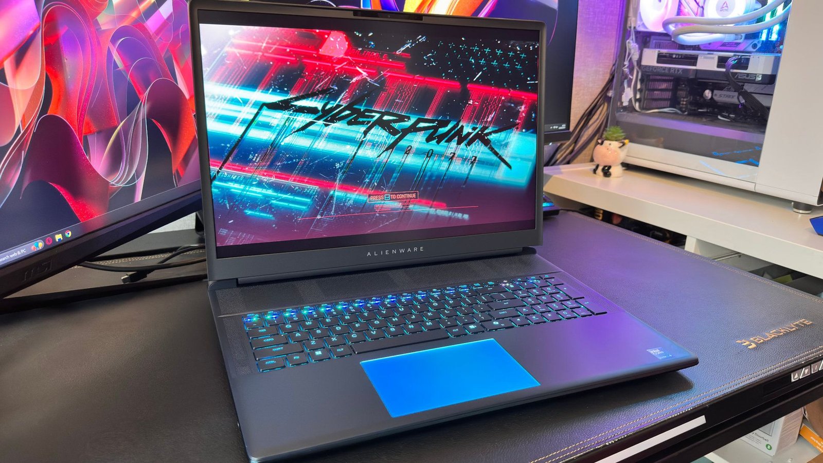 Hình ảnh một chiếc laptop chơi game Alienware 18 Area-51, màn hình hiển thị cảnh game Cyberpunk 2077, thể hiện sức mạnh đồ họa