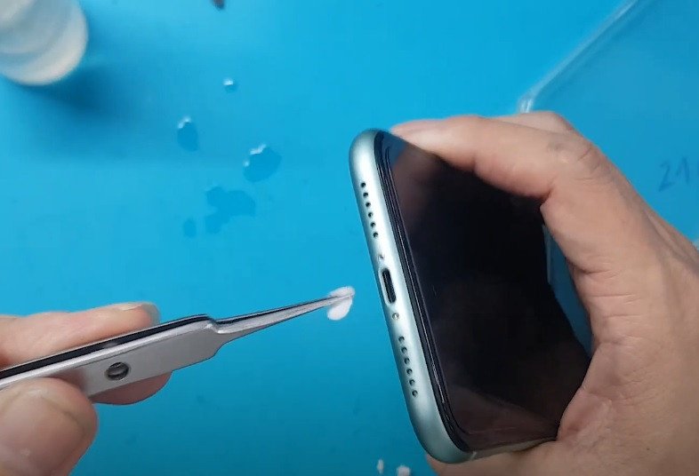 Hình ảnh một người đang dùng tăm bông để vệ sinh cổng Lightning trên iPhone