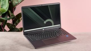 HP Chromebook Plus 15.6-inch trên bàn với tường hồng và cây xanh phía sau