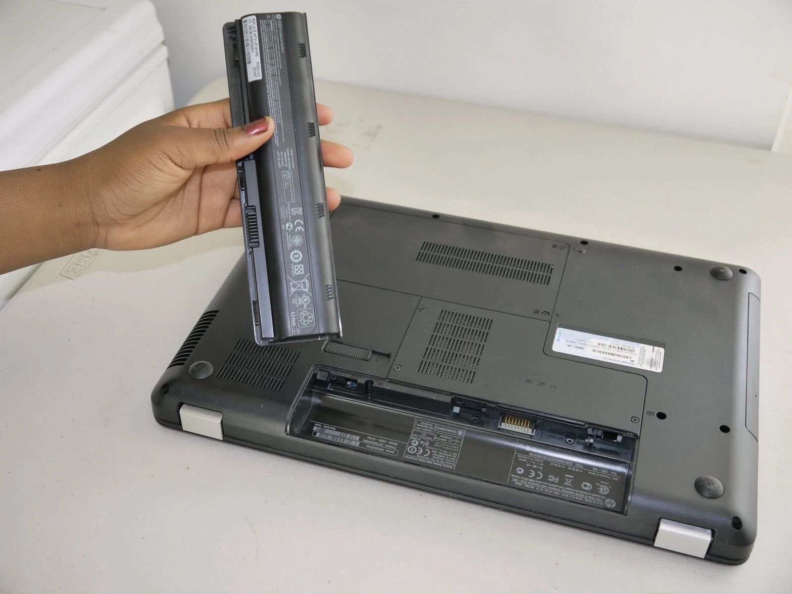 Kỹ thuật viên đang kiểm tra pin laptop HP trước khi thay thế