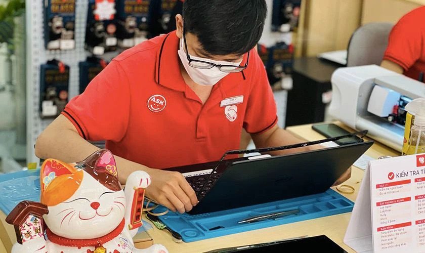 Kỹ thuật viên đang kiểm tra pin laptop phồng để thay thế tại trung tâm sửa chữa uy tín