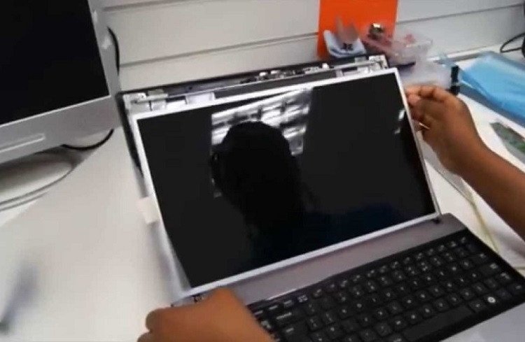 Kỹ thuật viên đang tháo lắp màn hình laptop để thay thế, một giải pháp triệt để cho vấn đề màn hình bị hở sáng nghiêm trọng.