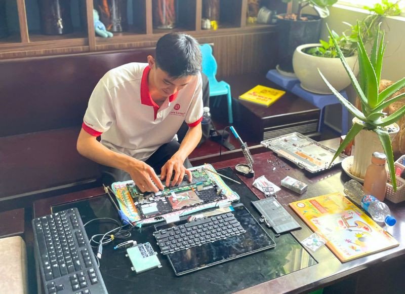 Kỹ thuật viên đang thực hiện sửa chữa laptop tận nơi cho khách hàng tại khu vực Thủ Đức.