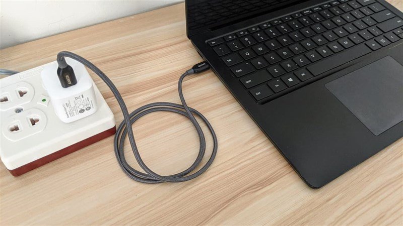 Laptop đang sạc pin khi vẫn hoạt động, minh họa việc sử dụng điện năng