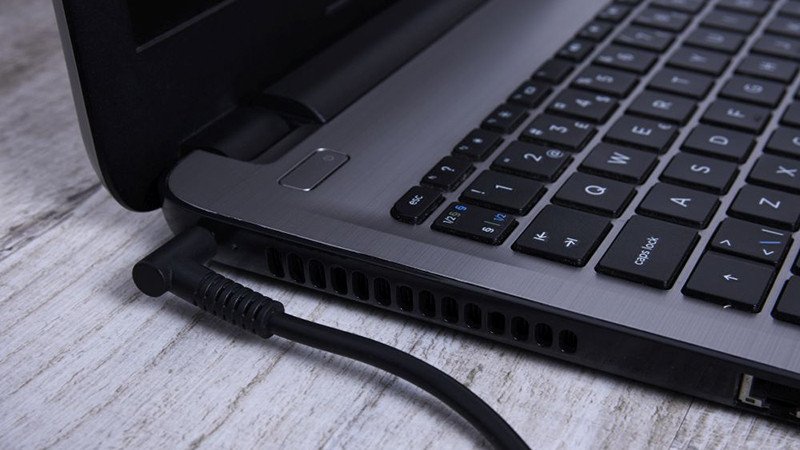 Laptop đang sạc và được được sử dụng cùng lúc, minh họa việc tránh vừa dùng vừa sạc khi pin chưa đầy, giúp bảo quản pin laptop