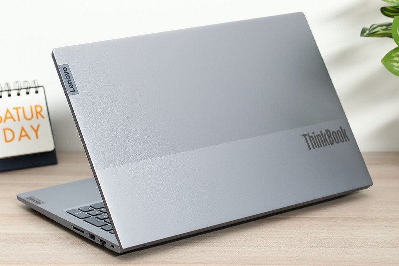 Laptop Lenovo ThinkBook màu xám than đang mở trên bàn làm việc với giao diện ứng dụng kinh doanh