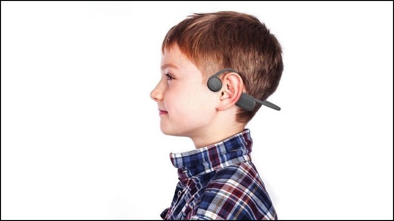 Một em bé đang vui vẻ đeo tai nghe truyền xương, cho thấy sự an toàn và phù hợp cho trẻ nhỏ