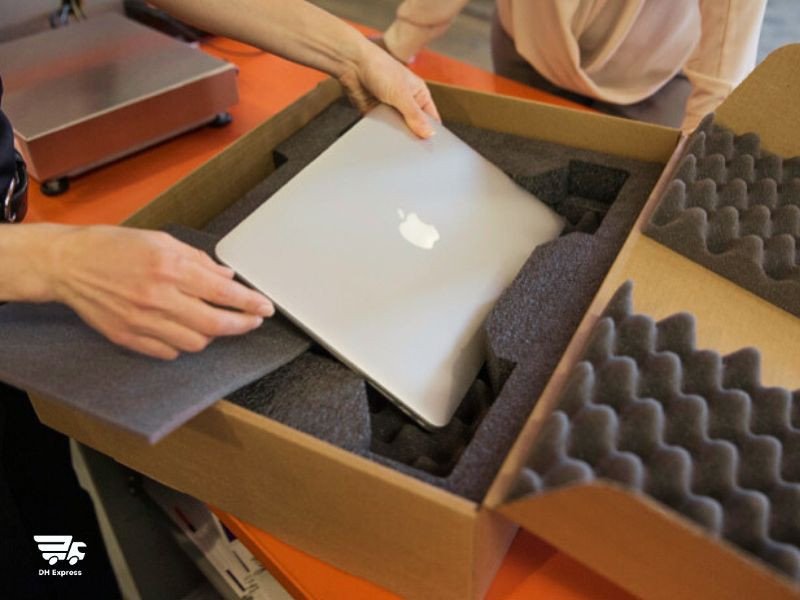 Một người đang cẩn thận bọc laptop bằng xốp hơi, minh họa quy trình đóng gói laptop an toàn
