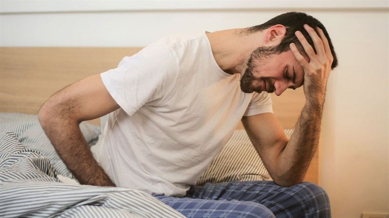 Một người phụ nữ đang ôm tai vì khó chịu, thể hiện nguy cơ tổn thương tai khi đeo tai nghe trong giấc ngủ không đúng cách.