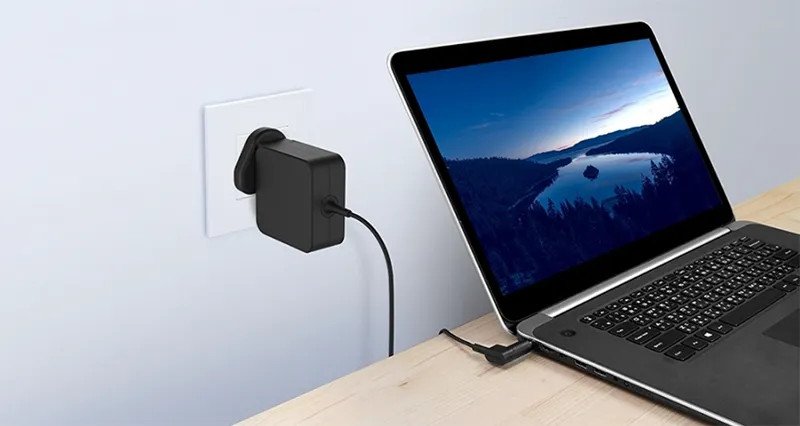 Một viên pin laptop và bộ sạc được đặt cạnh nhau