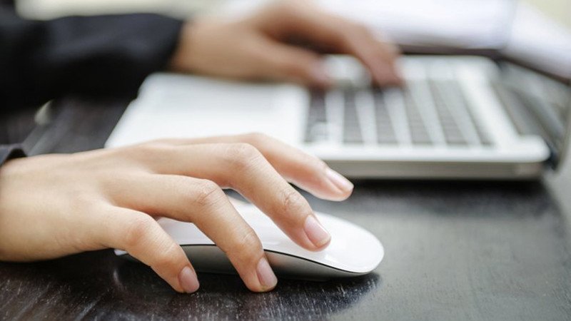 Người dùng đang làm việc trên laptop với chuột máy tính, tượng trưng cho việc sử dụng Auto Click hiệu quả