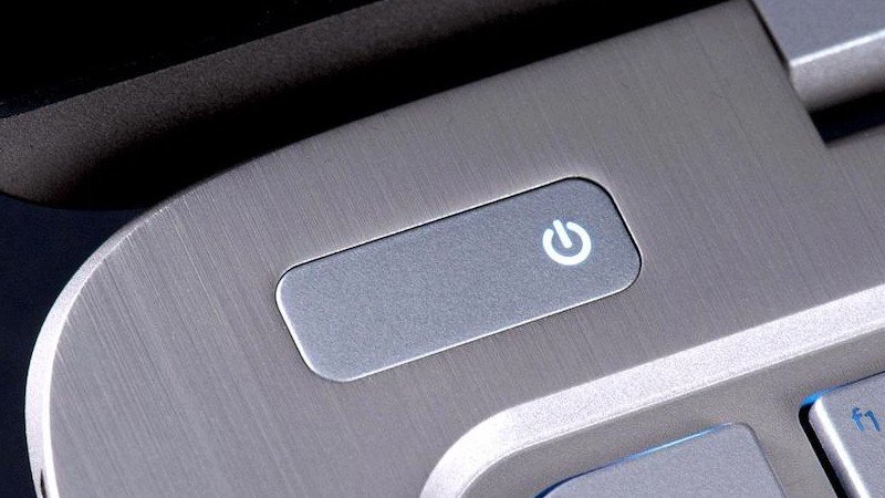 Người dùng đang nhấn giữ nút nguồn của laptop để tắt máy trong trường hợp khẩn cấp