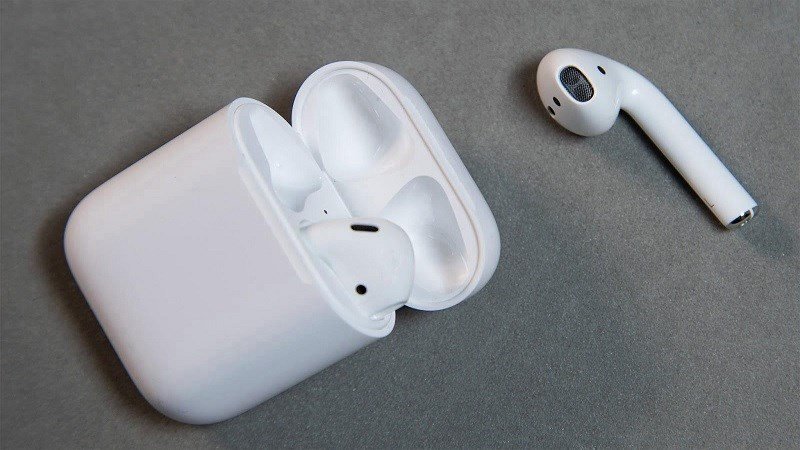 Người dùng đang nhấn giữ nút tròn phía sau hộp sạc AirPods để reset tai nghe