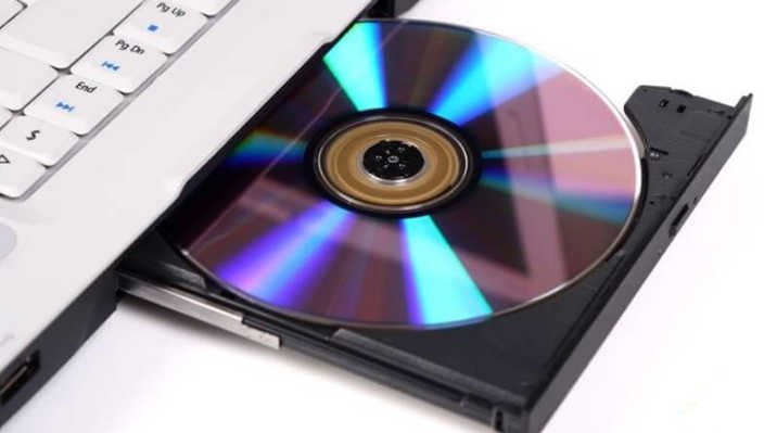 Người dùng đang thưởng thức nội dung từ đĩa CD trên laptop Dell, minh họa lợi ích khi sử dụng ổ đĩa quang.