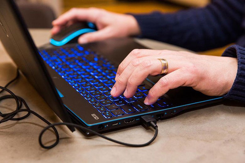 Người dùng làm việc với bàn phím laptop HP có đèn nền trong môi trường thiếu sáng