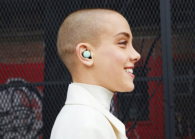 Tai nghe Google Pixel Buds màu trắng đang được đeo trên tai, hiển thị tính năng phiên dịch trực tiếp từ ứng dụng.