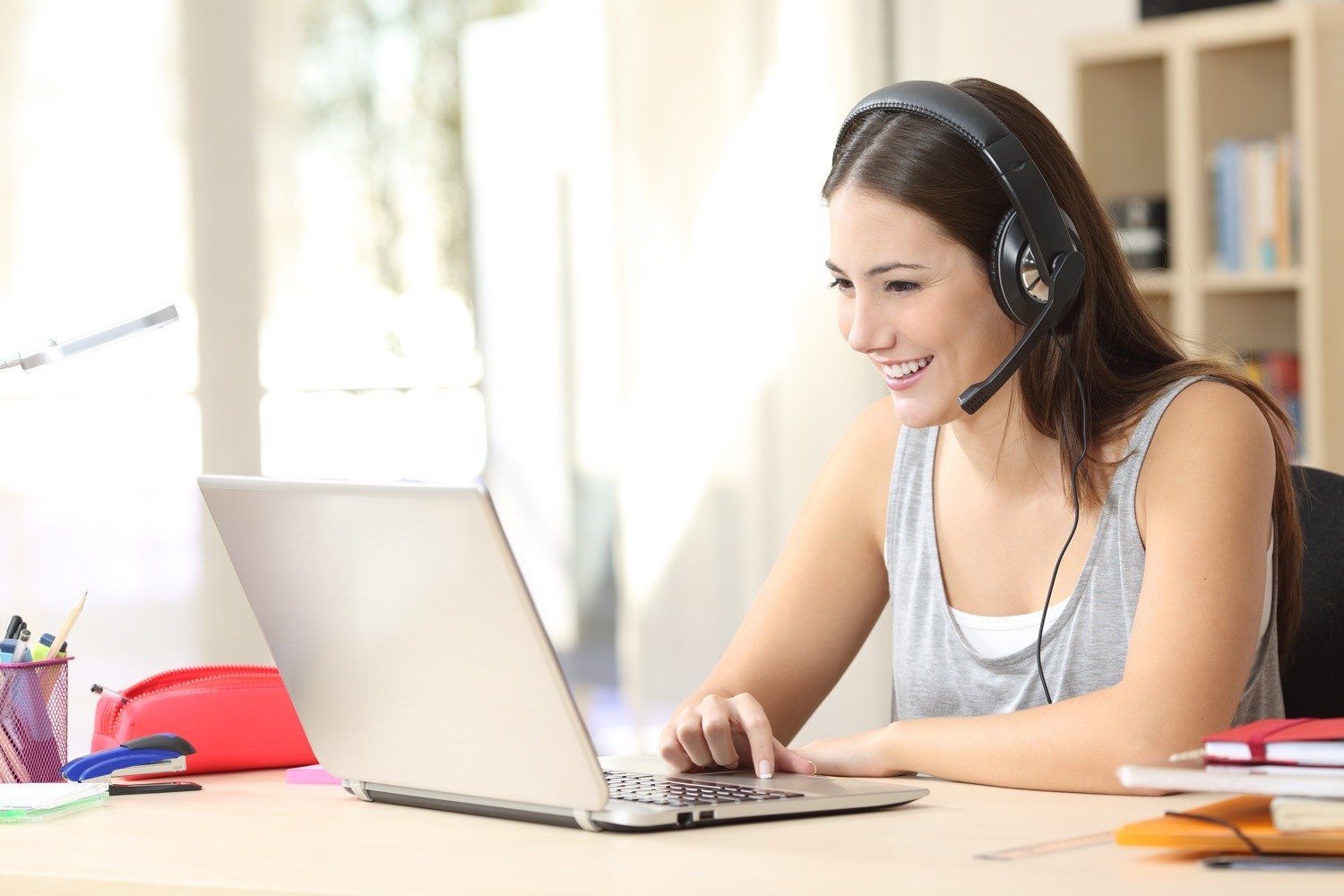 Tai nghe nhét tai có mic màu trắng đặt cạnh laptop trên bàn làm việc