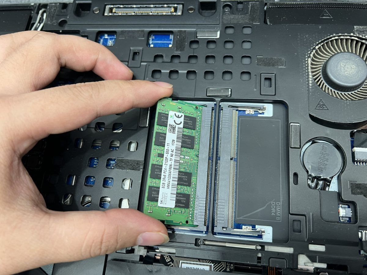 Thao tác gỡ thanh RAM cũ khỏi khe cắm trên laptop