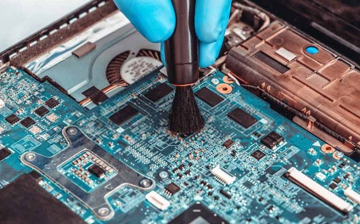 Thợ kỹ thuật đang vệ sinh bên trong laptop, làm sạch bụi bẩn và thay keo tản nhiệt để cải thiện hiệu suất