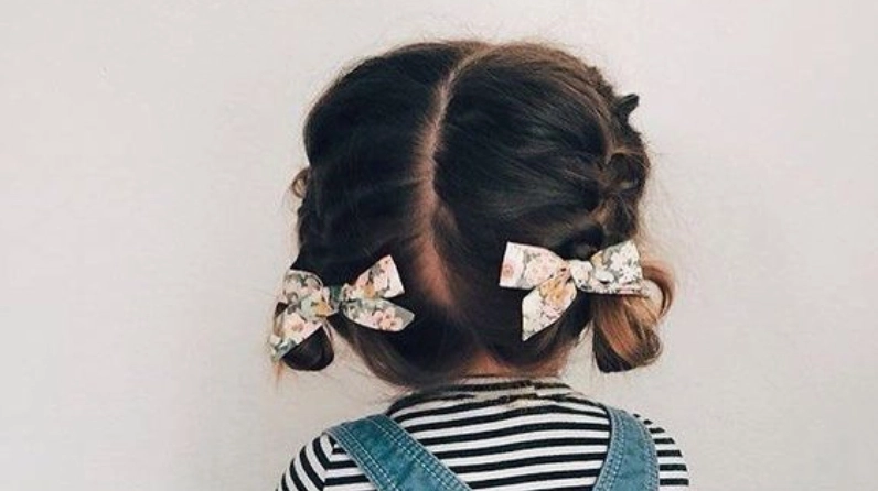 Bé gái với mái tóc cột hai bên và nơ xinh